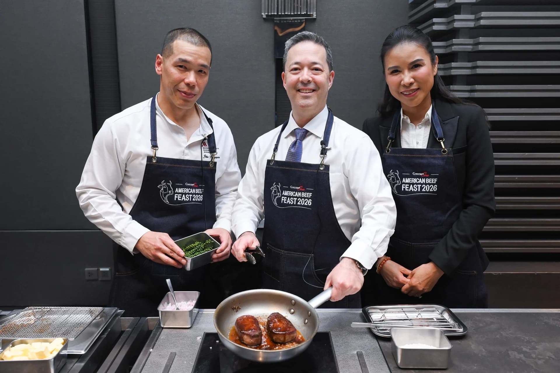 A chef and guests presenting a pan of beef at a cooking station.