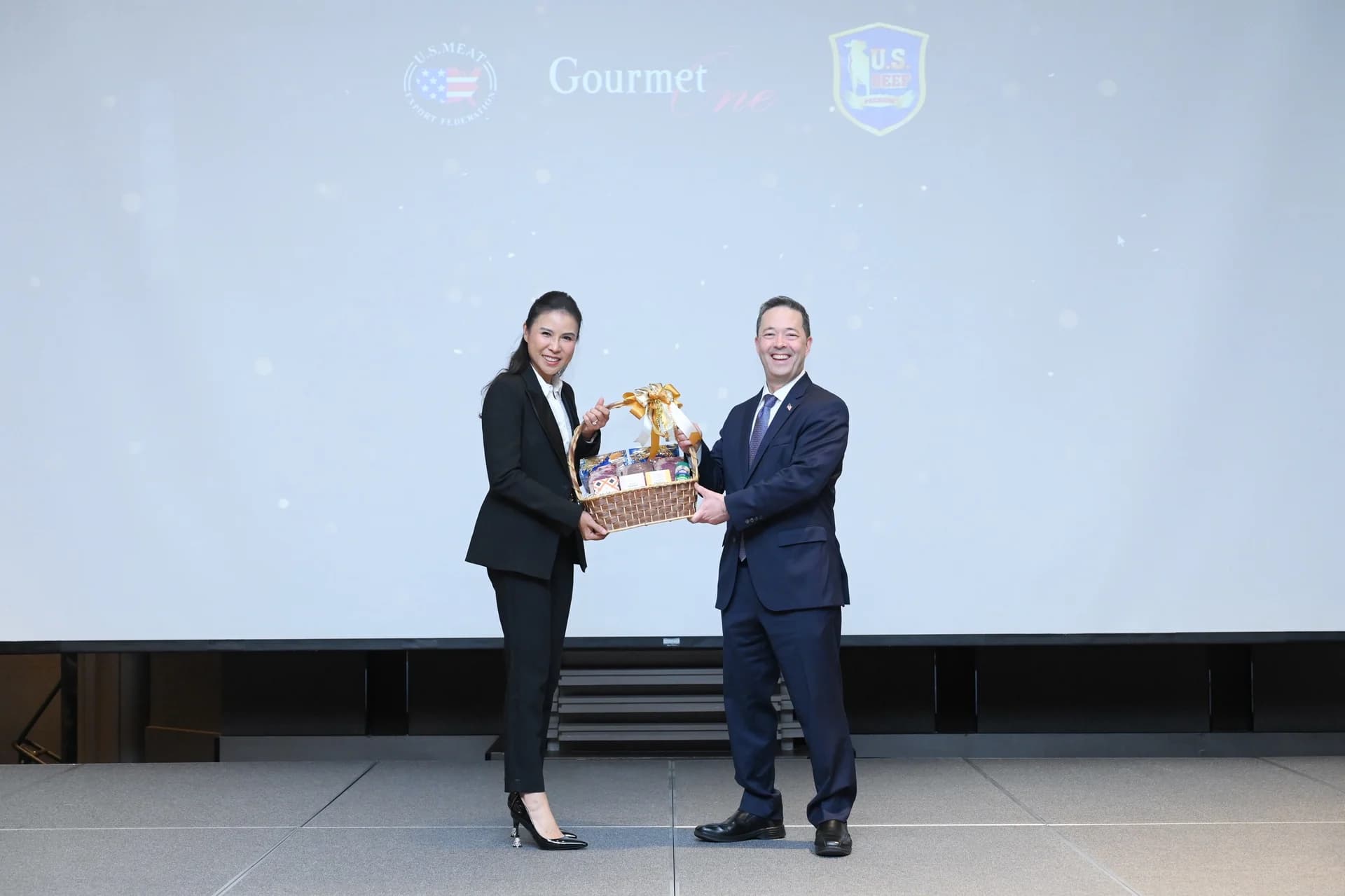 Two guests presenting a gift basket on stage at the campaign launch.